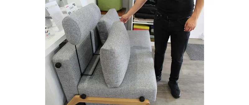 Der Bügel der Kopfstütze FLIP wird einfach zwischen Sofapolster und Rückenkissen gesteckt - hier beim CUBED 140 Schlafsofa
