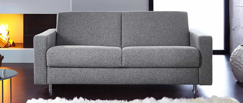 Das HAMBURG DELUXE Schlafsofa mit breiten Armlehnen und grauem Stoffbezug
